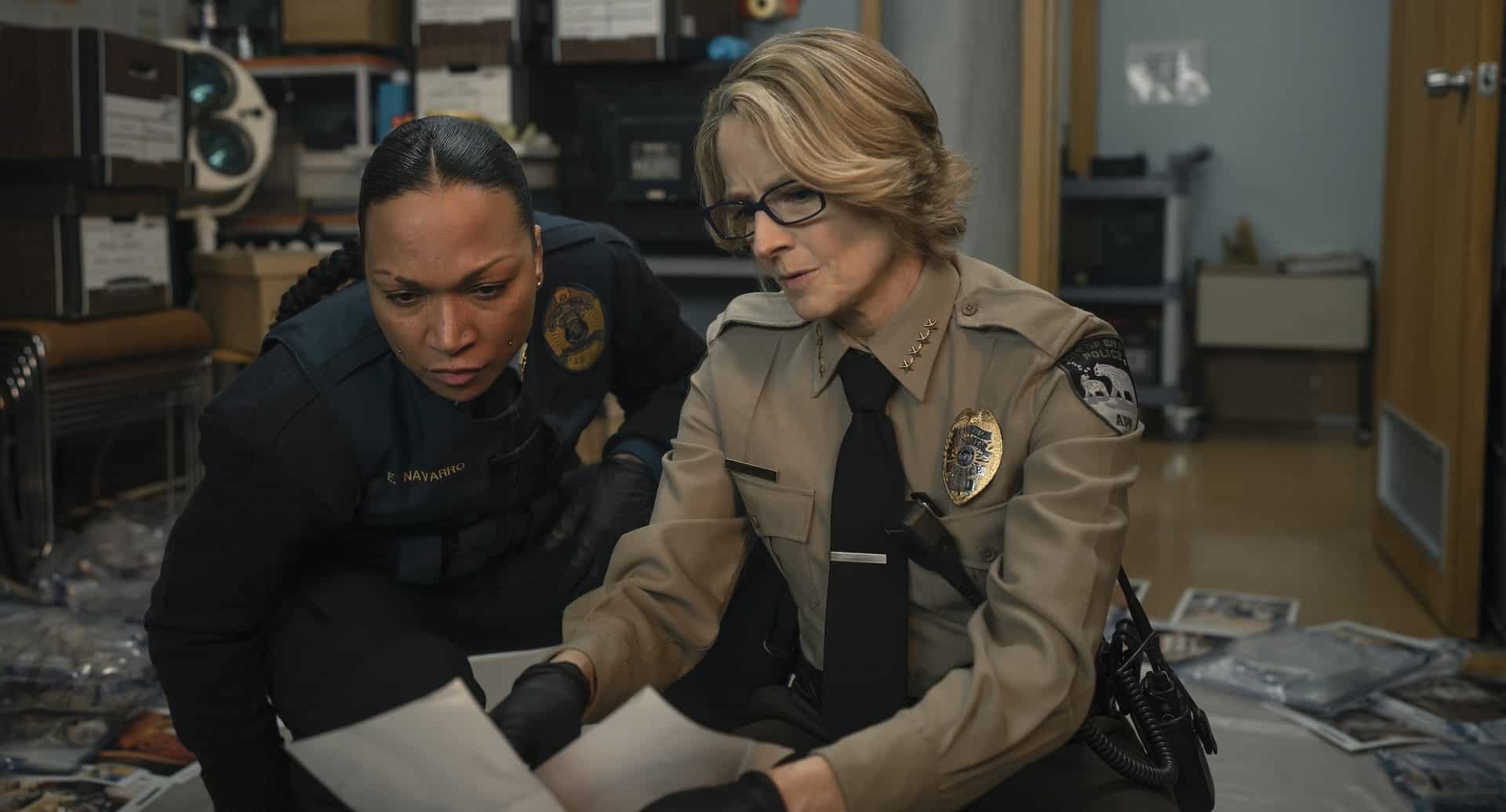 Two women in police uniforms looking at a piece of paper.