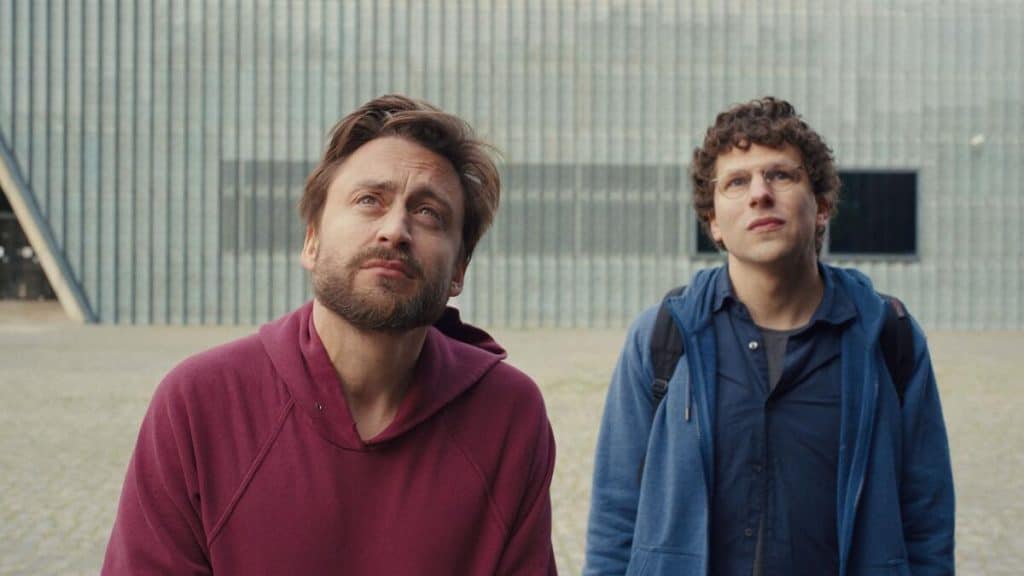 Two men standing next to each other in front of a building.