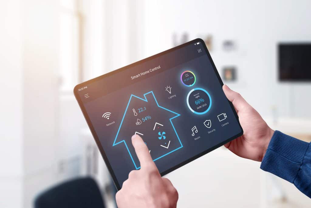 A man is holding a tablet with a smart home app on it.