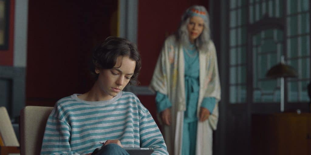A woman sitting in a chair looking at a tablet.