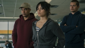 Three individuals standing in an office space, appearing focused and determined.