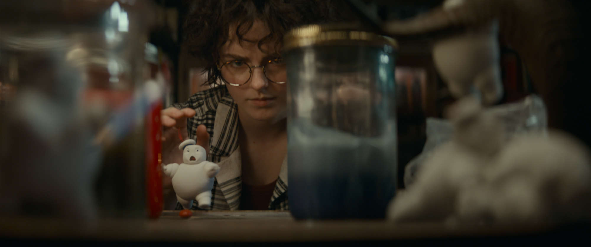 A person peering through a shelf lined with various figurines and objects.