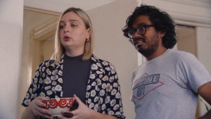 Two individuals standing in a hallway with a surprised expression, one holding a bowl.