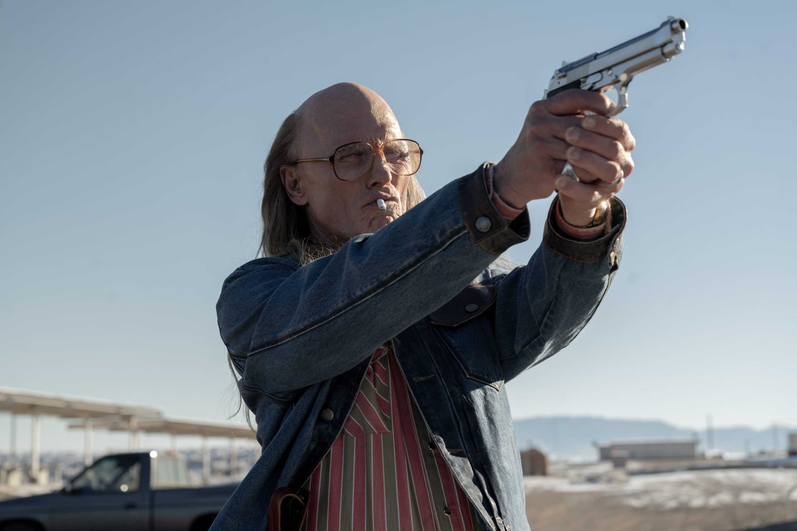 A man holding a gun in the desert.