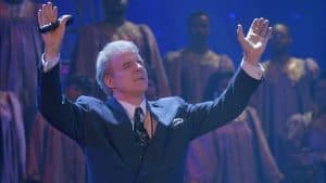 A man in a suit with his hands up in the air.