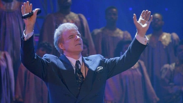 A man in a suit with his hands up in the air.