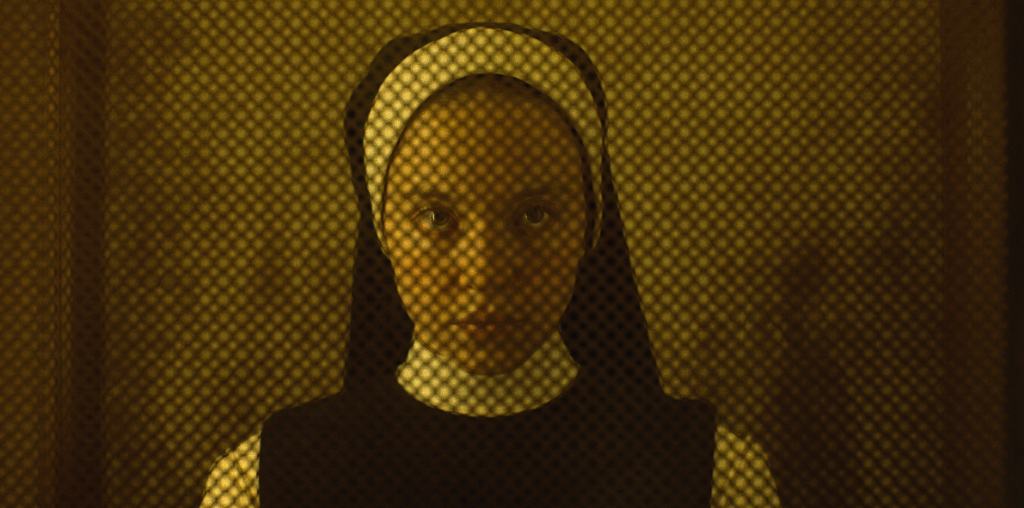 A woman in a traditional headscarf with a patterned backdrop casting a dotted shadow on her face.