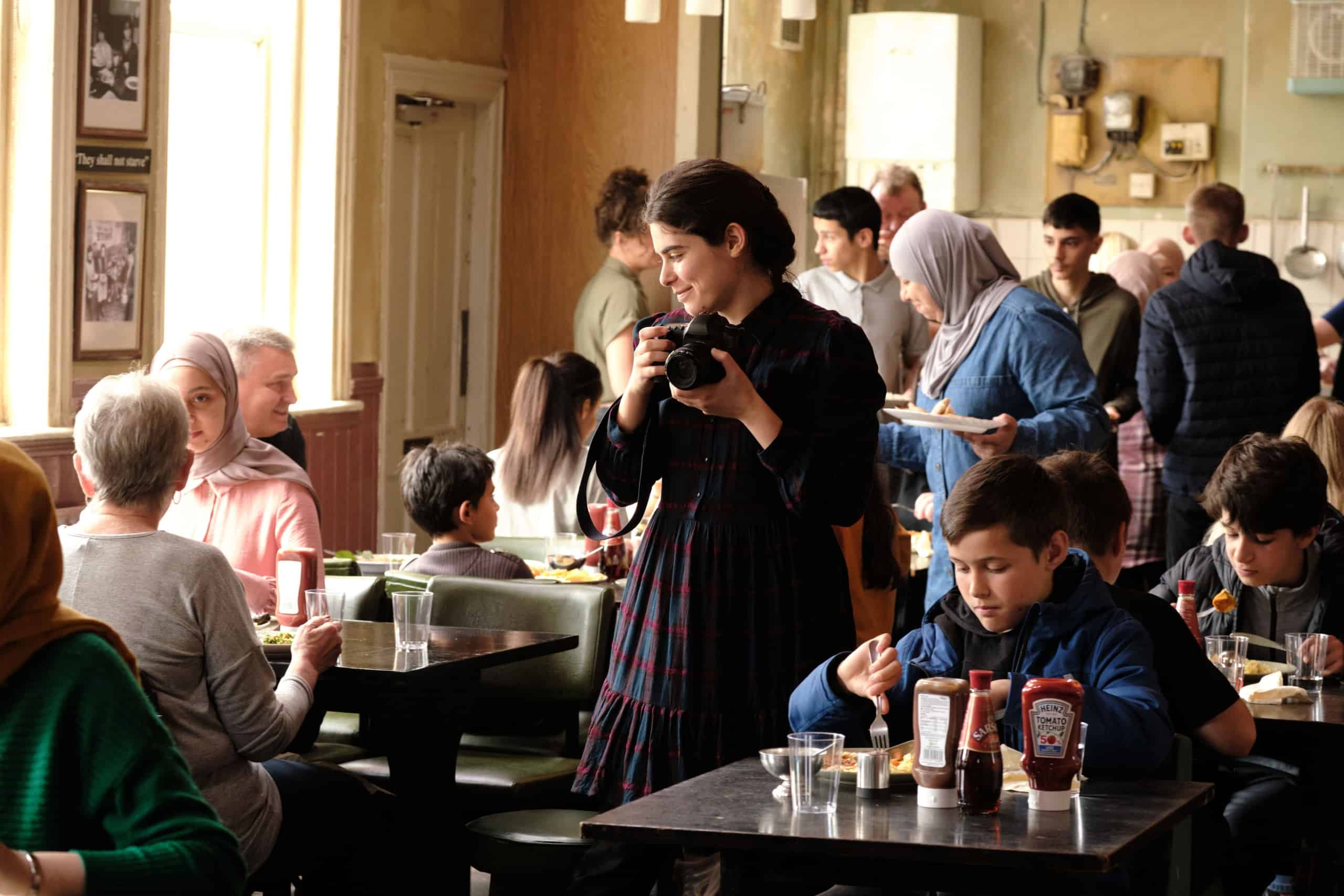 Woman taking a photograph in a bustling café.