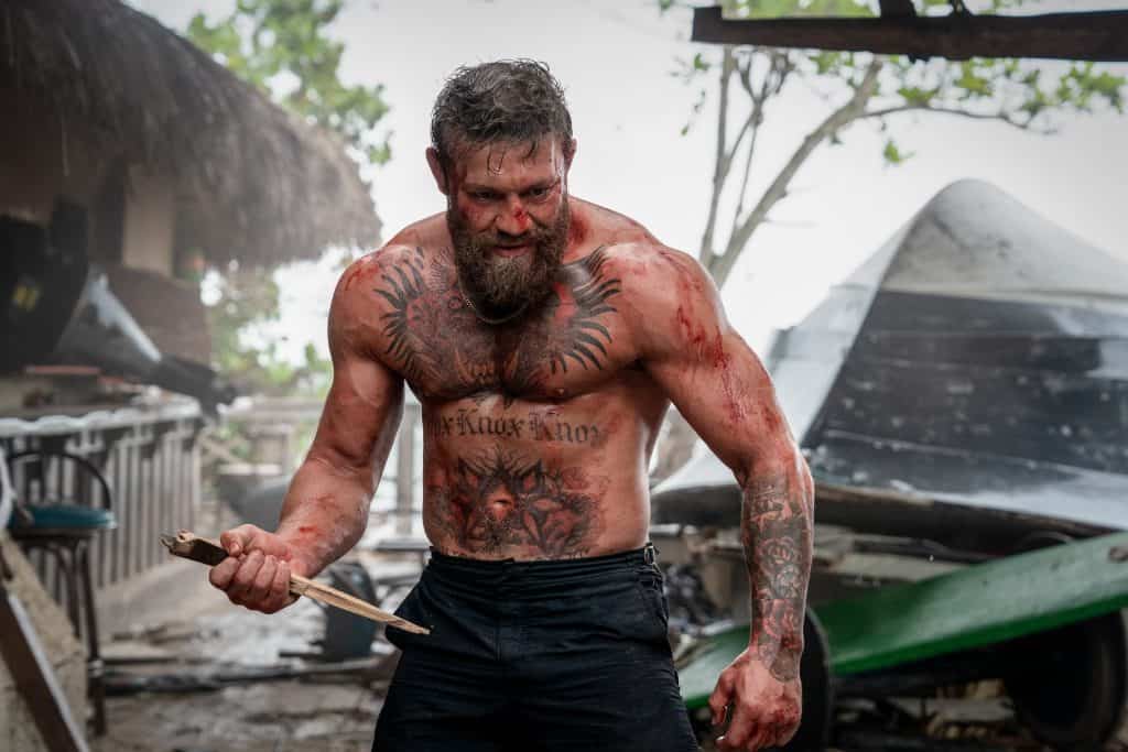 A man with a beard and tattoos holding a baseball bat.