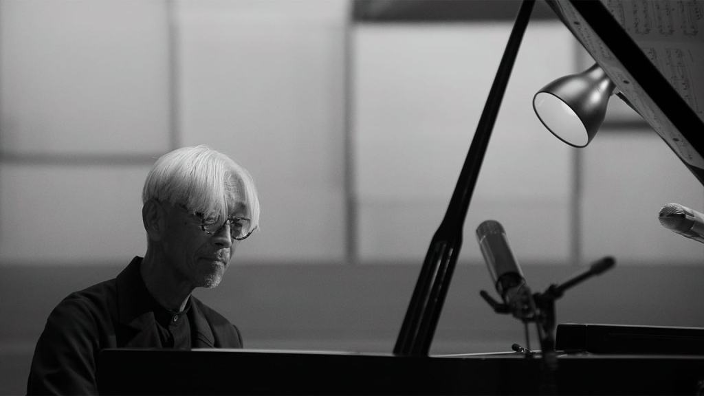 Pianist focused on sheet music during a black and white performance scene.