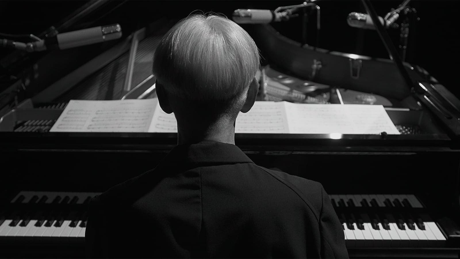 Pianist preparing to play with sheet music on piano.