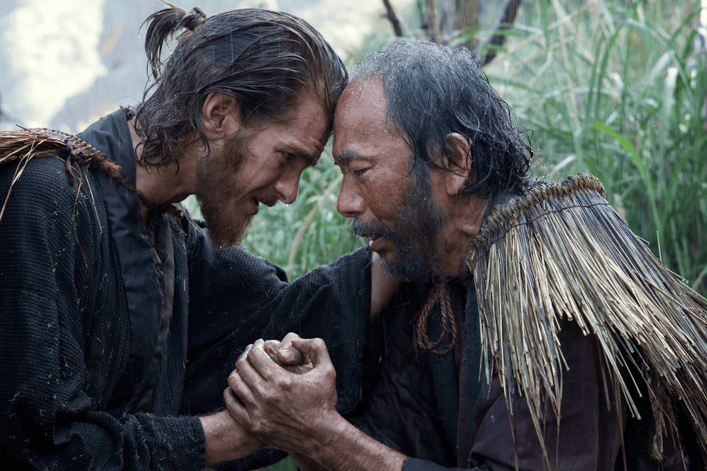 Two men in historical clothing emotionally holding hands.
