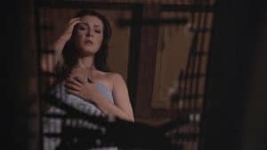 A woman in a blue bathing suit is standing in front of a cage.