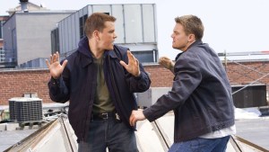 Two men having a discussion on a rooftop with one man gesturing with his hands while the other appears to be speaking to him.