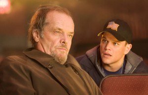 Two men focused on something out of frame, one older with a thoughtful expression, the other younger wearing a cap with an american flag patch.