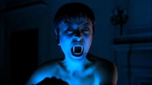 A person with a vampiric appearance displaying fangs in a dimly lit room.
