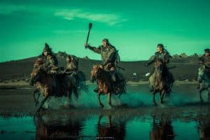A group of men riding horses in a watery area.