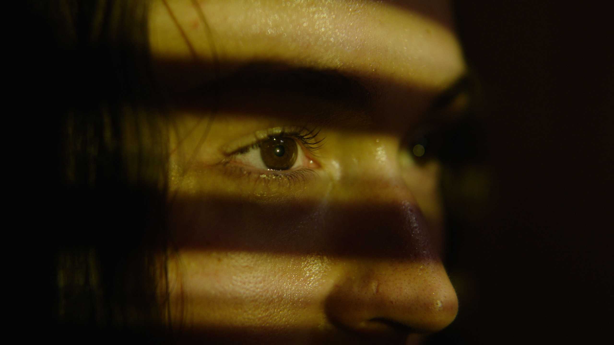 Close-up of a person's face with shadows casting stripes across it.