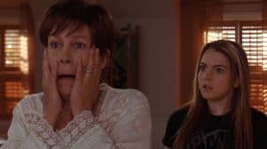 Two women with surprised expressions, one with hands on her cheeks, the other looking intently forward.