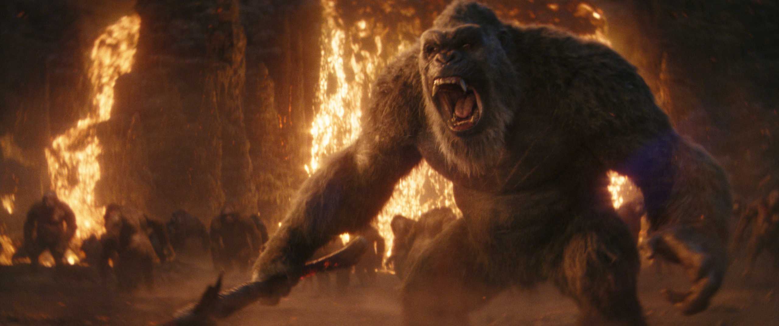 A giant gorilla in a fiery scene roars aggressively while wielding a weapon.