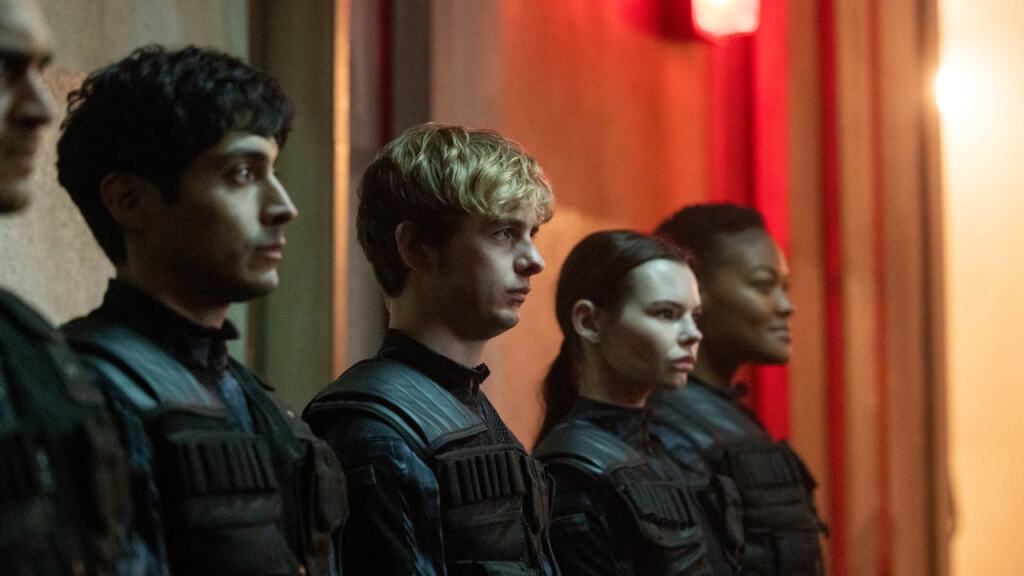 Four individuals in tactical gear standing in a row with focused expressions.