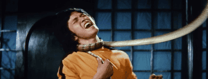 A person appears distressed while being constricted by a large snake.
