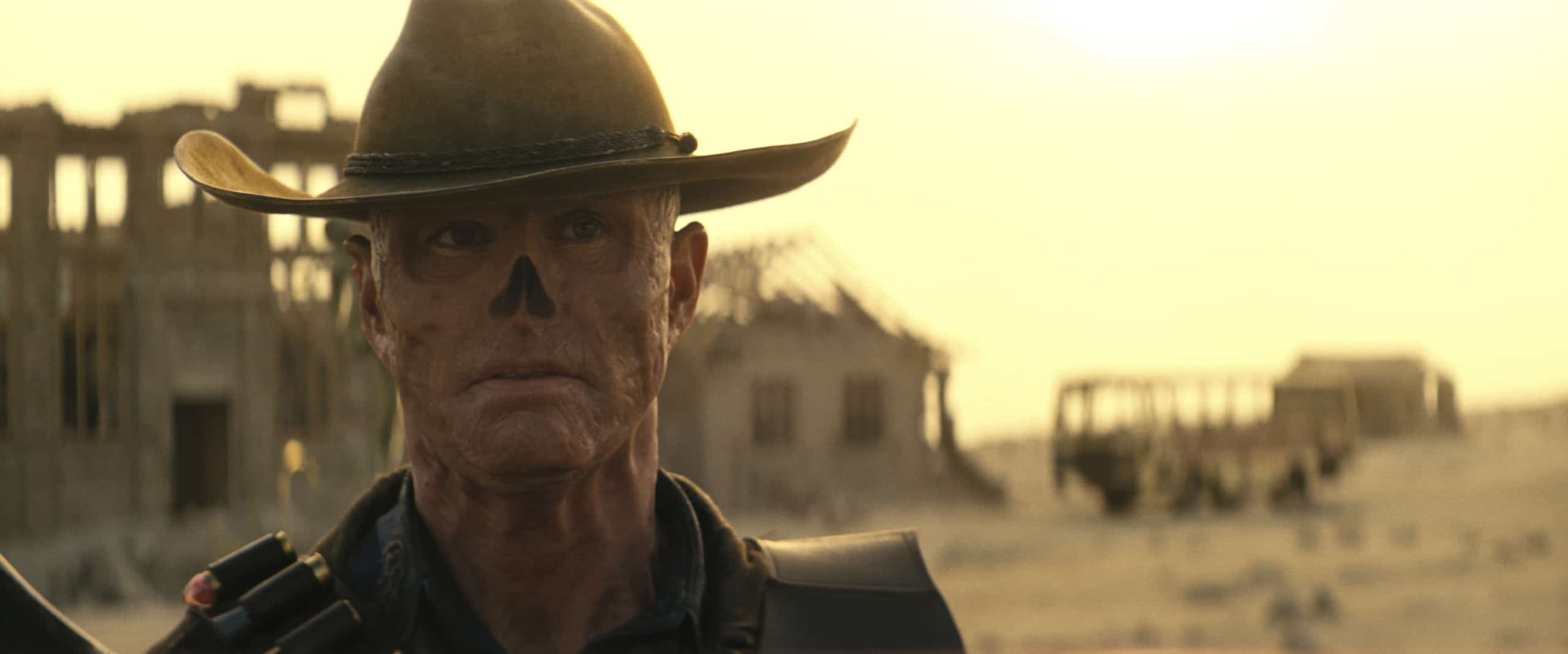 A character in cowboy attire with face paint standing in a desert landscape.