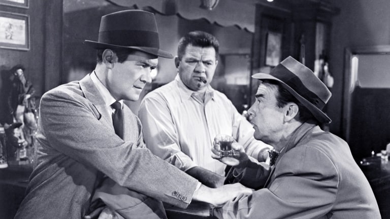 Film Noir: The Dark Side Of Cinema XVIII Blu-Ray Review – A Gritty Trio Of Deception & Murder Three men in a vintage setting, with one holding a drink and engaging in a serious conversation.