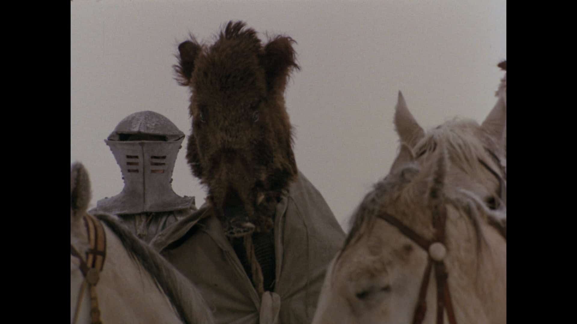 A person in medieval armor and a bear headdress rides alongside another mounted individual in a historical setting.