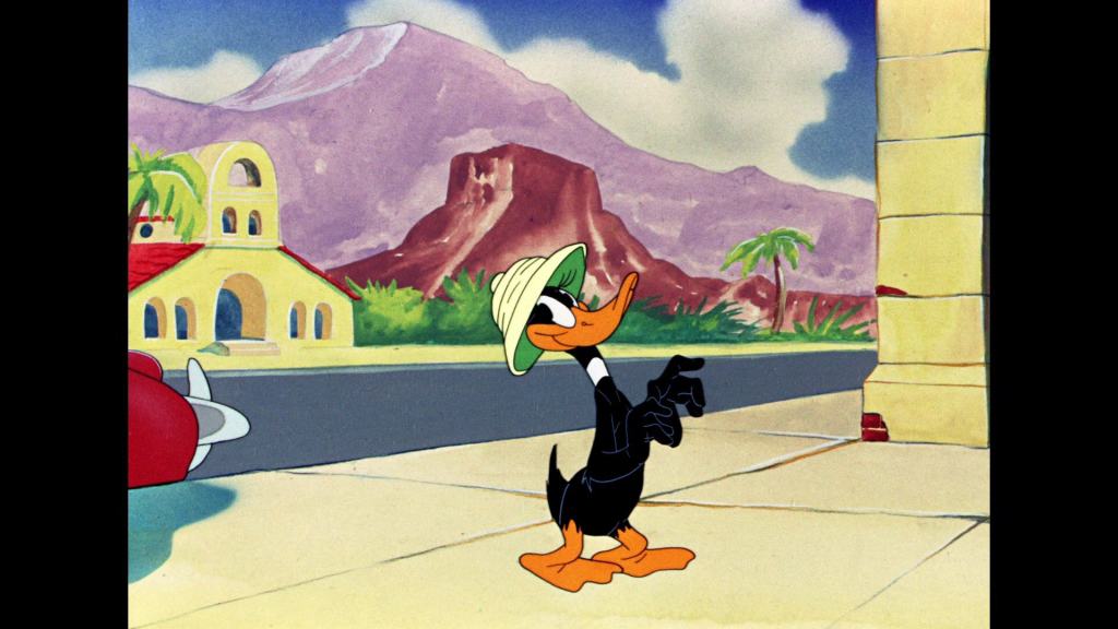 Animated duck character strolling with confidence against a colorful backdrop with mountains and spanish-style architecture.