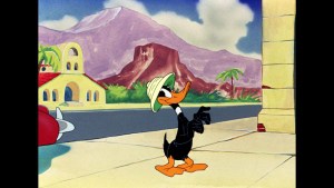 ‘Looney Tunes’ Collector’s Choice: Volume 3 Blu-Ray Review – A Reliable Source Of Fun Animated duck character strolling with confidence against a colorful backdrop with mountains and spanish-style architecture.