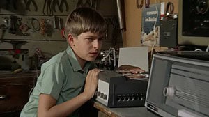 ‘Misunderstood’ (1966) Blu-Ray Review – The Heartbreaking Tragedy Of Being Overlooked A young boy in a workshop listening intently to a reel-to-reel tape recorder, surrounded by various tools hanging on the wall.
