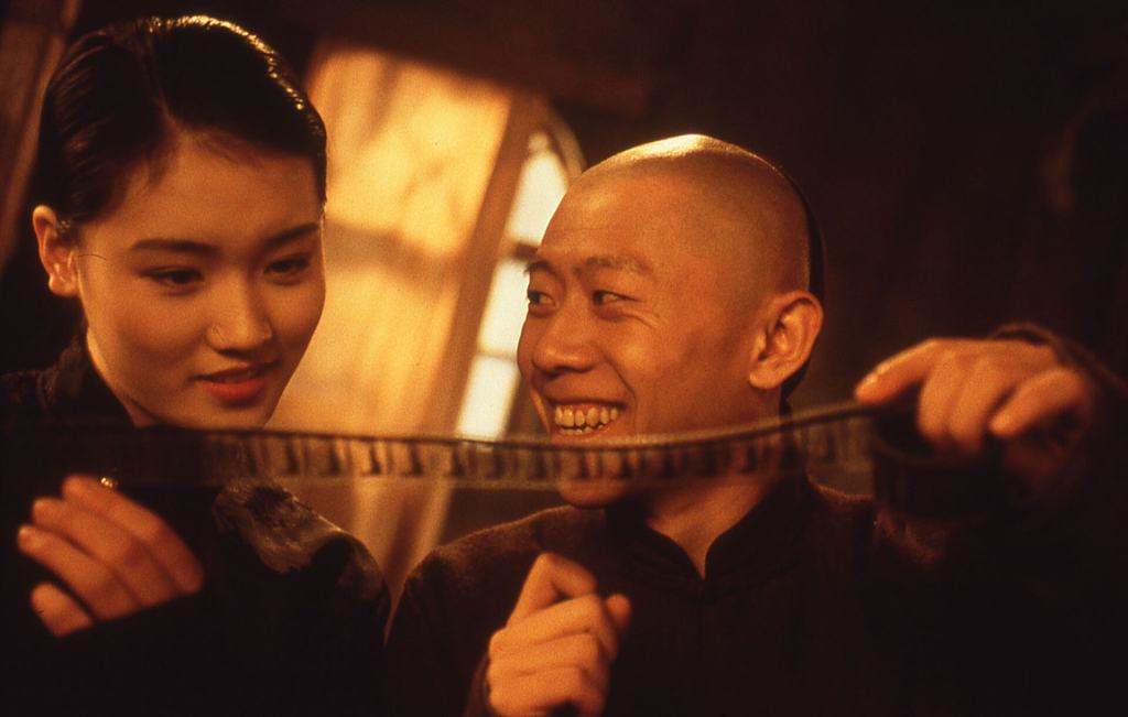 A man and woman examining a strip of film with interest and amusement.