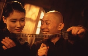 A man and woman examining a strip of film with interest and amusement.