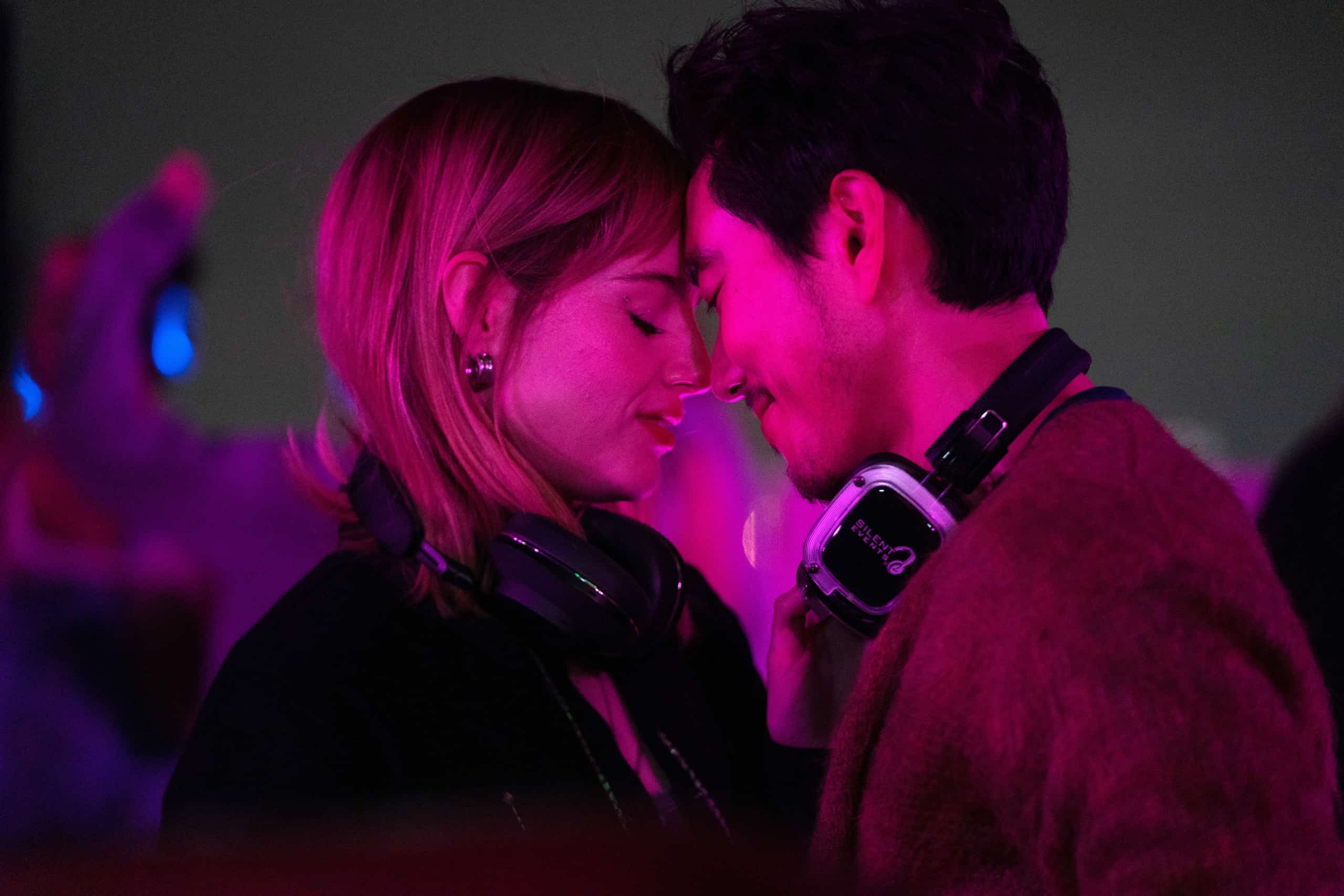 Two people wearing headphones sharing an intimate moment at a silent disco.