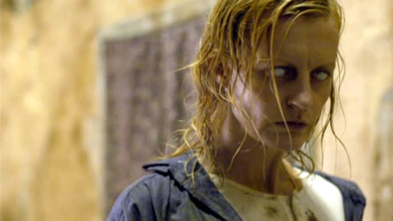 A woman with wet, disheveled hair, looking intensely off-camera, set against a blurred indoor background.