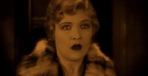 A surprised-looking woman with fur-collar attire in a sepia-toned vintage image.