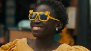 ‘The Little Girl Who Sold The Sun’ + ‘Le Franc’: Two Films By Djibril Diop Mambéty Blu-Ray Review – Rewarding Cinema A woman in a yellow dress and playful sunglasses smiles broadly.