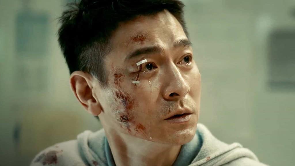 A man with a bruised and bloodied face looks off to the side, his expression filled with concern and distress.