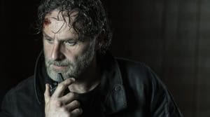 Andrew Lincoln Returning to ‘The Walking Dead’, As A Director A man with a bruised face looks thoughtful while holding a pen to his lips.