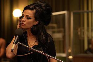 Universal To Release The Amy Winehouse Biopic ‘Back To Black’ On Blu-Ray Very Soon A woman with a dramatic beehive hairstyle sings into a microphone, wearing large hoop earrings and stylish makeup in a warmly lit room.