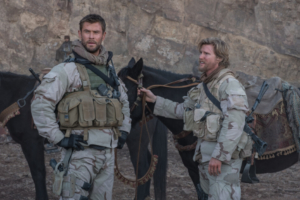 ’12 Strong’ 4K UHD Blu-Ray Review – Chris Hemsworth War Picture Beats You Down With Blunt Force Two men in military gear standing with a horse in a rocky terrain, looking into the distance.