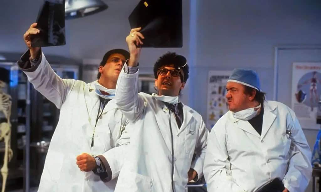 Three doctors in white coats examining x-ray films in a hospital room.