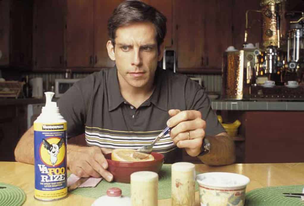 Man sitting at a kitchen table, looking at the camera while eating cereal, with a can of "yafoo raze" insecticide on the table.