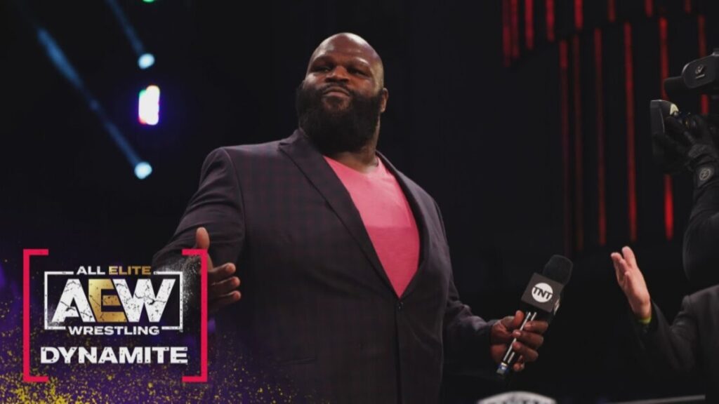 A man in a checkered blazer and pink shirt is holding a microphone with the TNT logo. The AEW Wrestling: Dynamite logo is displayed in the bottom left corner of the image.