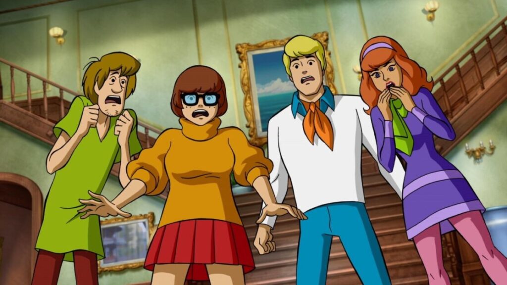 Four animated characters look startled and fearful inside a large, well-furnished room with a staircase in the background.