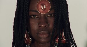 Three Revolutionary Films By Ousmane Sembène Criterion Collection Blu-Ray Review – A Vital Slice Of African Cinema A person with braided hair wears an ornament on their forehead and large earrings. The ornament and earrings have a natural, shell-like design.