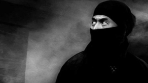 The Shinobi Collection Blu-Ray Review – Classic Ninja Series Sets The Standard Black and white image of a person with a stern expression, wearing a ninja mask that covers the lower half of the face.