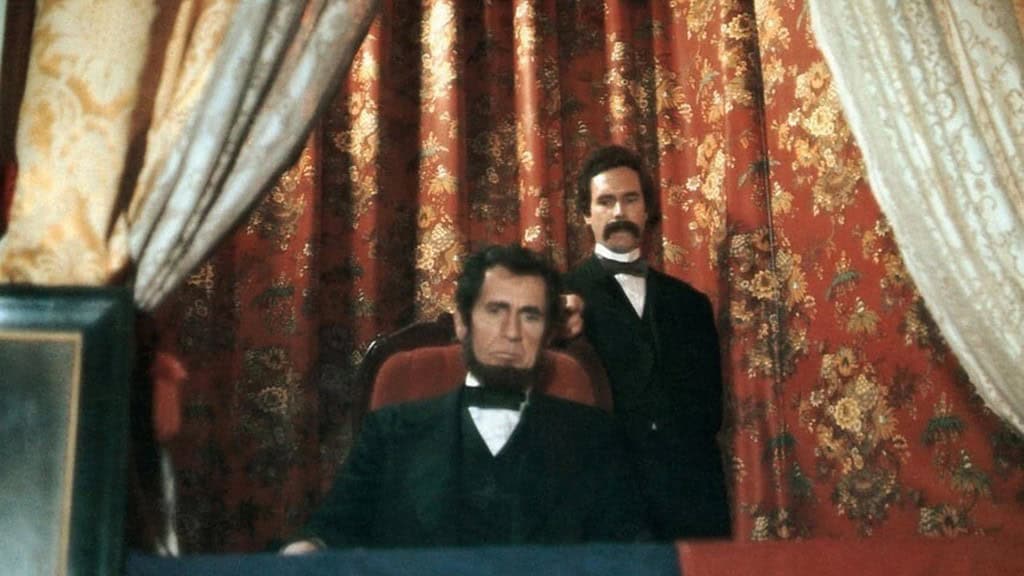 A still from a film showing an actor portraying abraham lincoln sitting solemnly in a theater box with another actor standing behind him, both in period costumes.