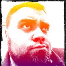 Colorized photo of a bearded person looking up with a thoughtful expression.